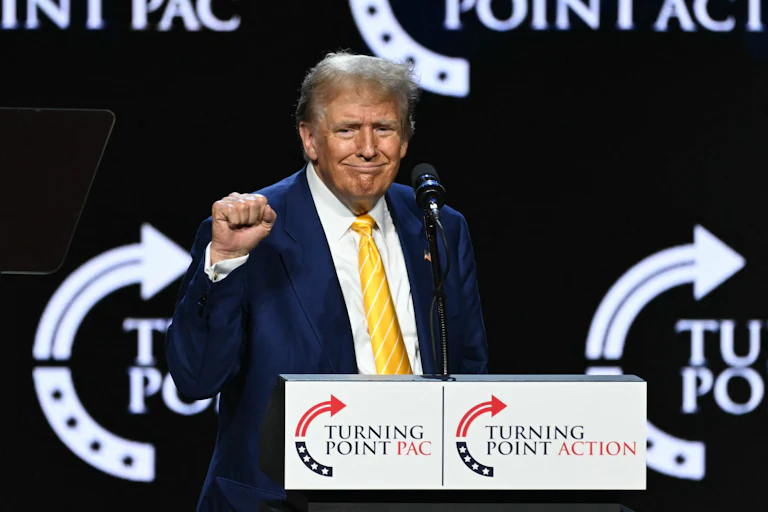 Donald Trump holds up his fist as he stands at a podium