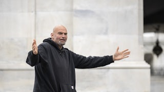 John Fetterman wearing his customary hoodie holds out his arms