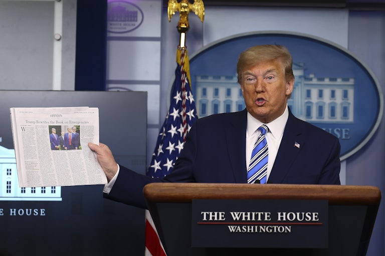 President Donald Trump holds up The Wall Street Journal during a coronavirus briefing