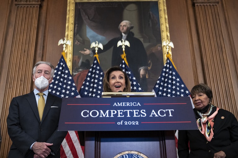 Speaker of the House Nancy Pelosi stands behind a podium labeled "America Competes Act of 2022."
