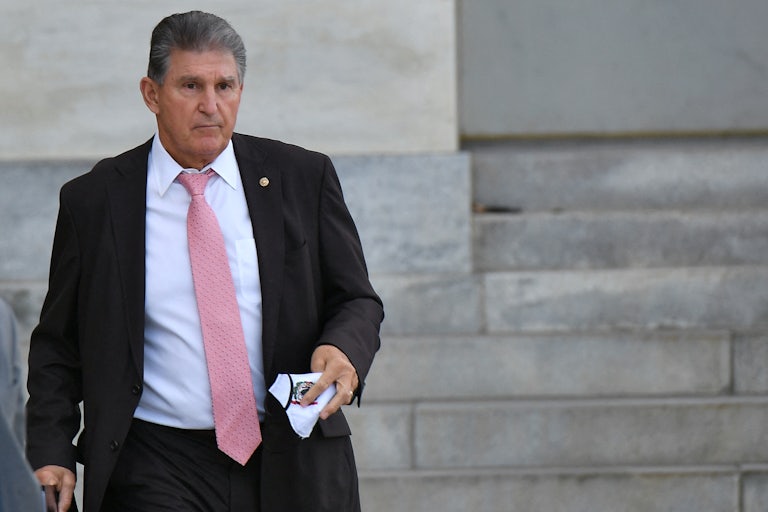 Senator Joe Manchin stands outside holding a napkin.