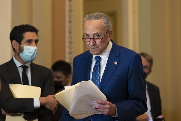 Chuck Schumer stands holding his notes during a meeting of the Senate Democratic caucus.