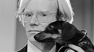 Artist Andy Warhol poses with his dauschund, Archie.