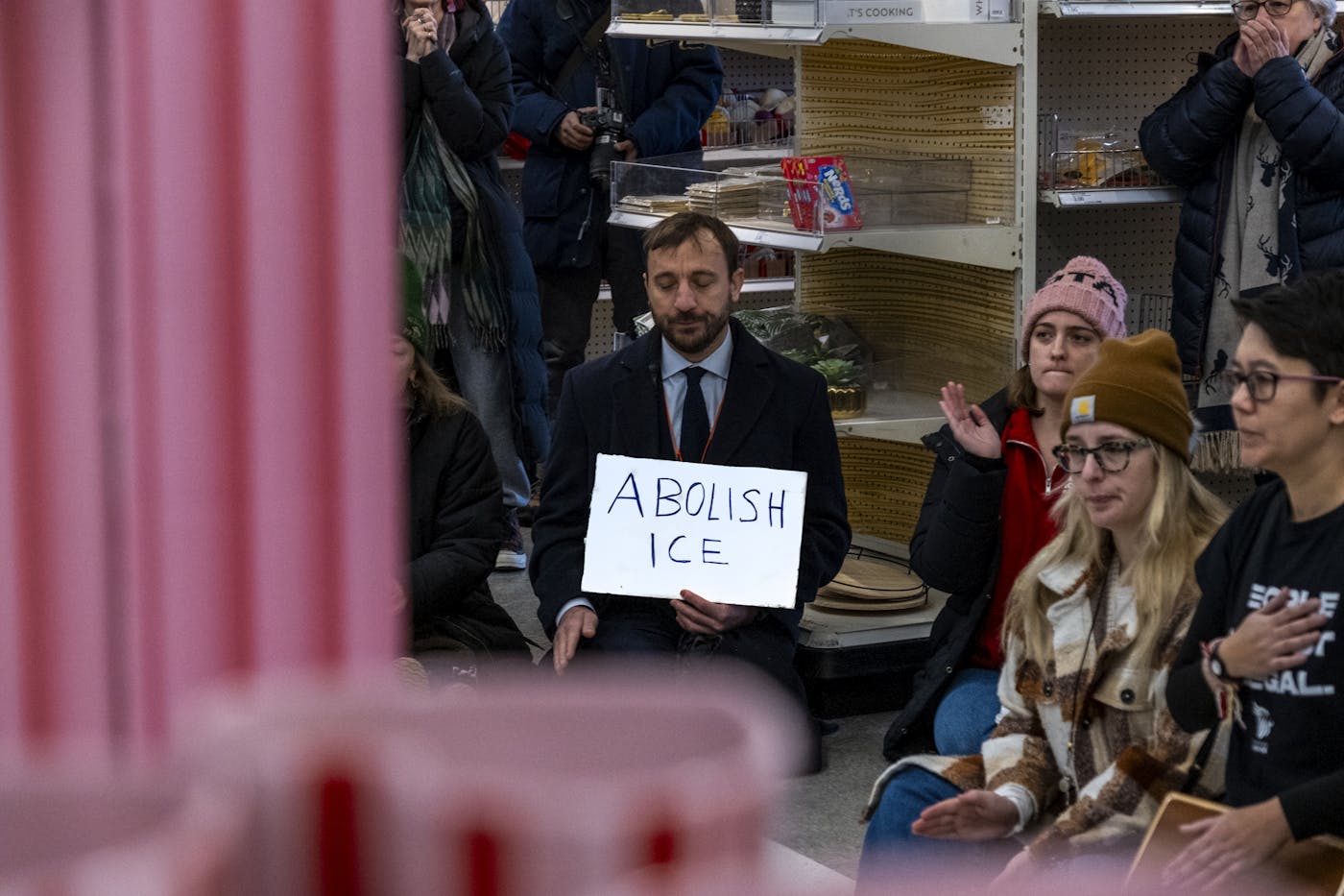 A man at a protest inside a Minneapolis Target store holds a sign that says ABOLISH ICE
