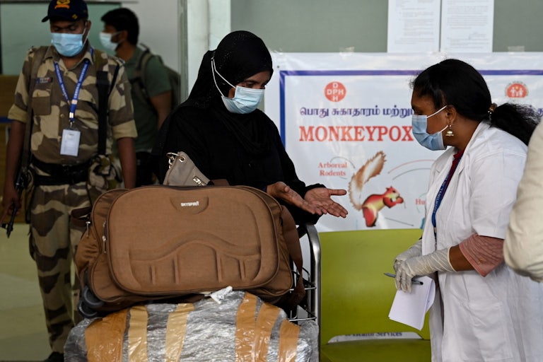 A health worker examines a woman's hands at an airport checkpoint.
