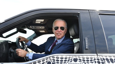 Joe Biden wearing sunglasses and looking out the window of a Ford F150 truck.