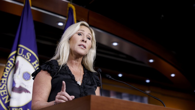 Marjorie Taylor Greene stands at a lectern.