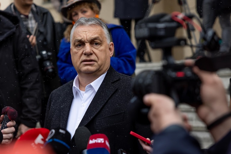 Viktor Orban speaks before a sea of microphones.