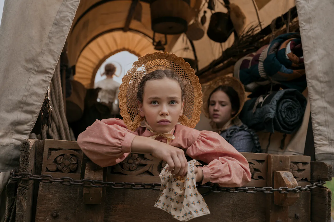 An episodic image from Little House on the Prairie. showing Laura (Alice Halsey) in the back of a wagon as she heads West.