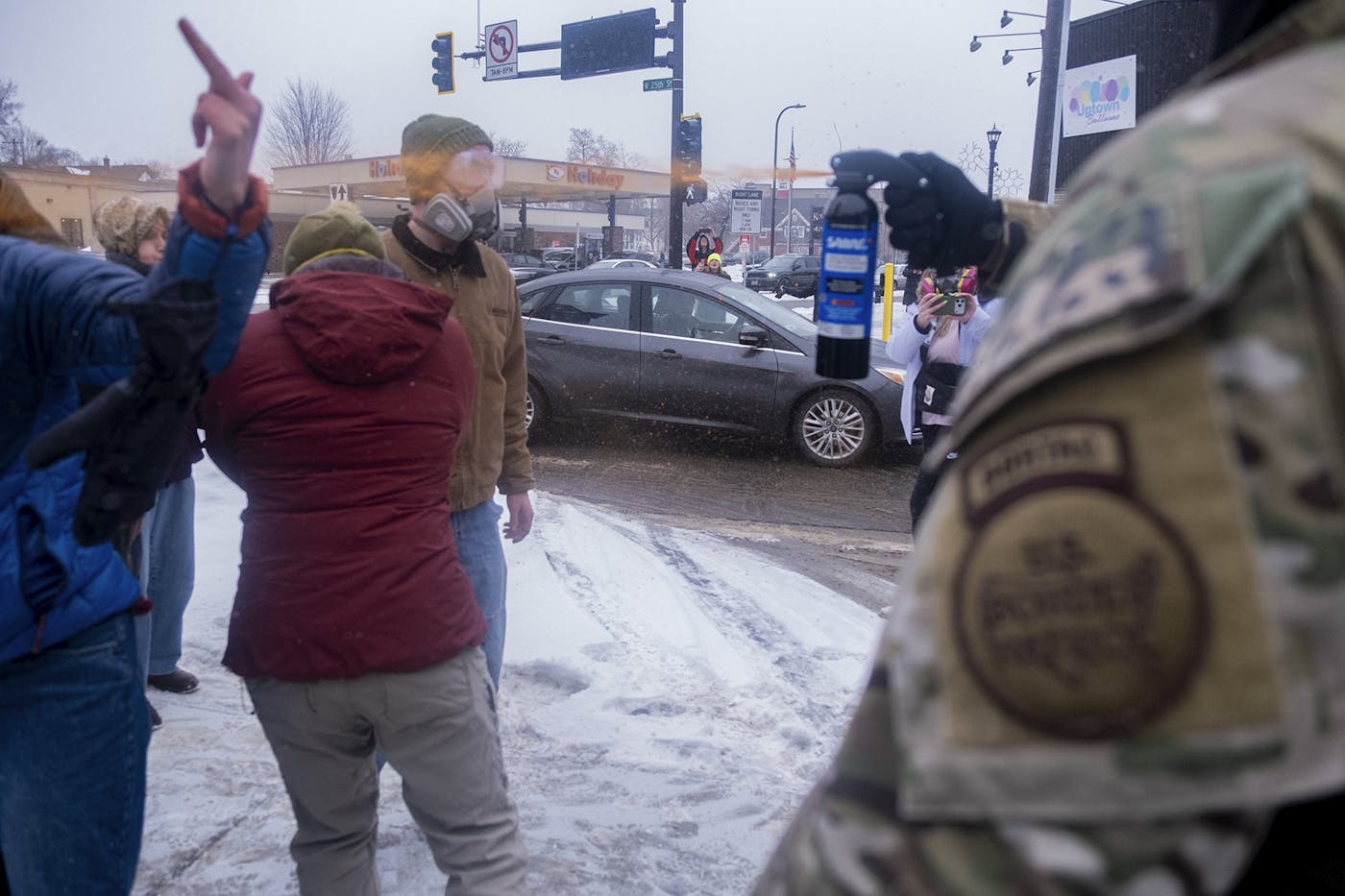 An ICE agent pepper-sprays protesters in their faces while one protester is giving him the finger at a gas station in Minneapolis January 21, 2026.