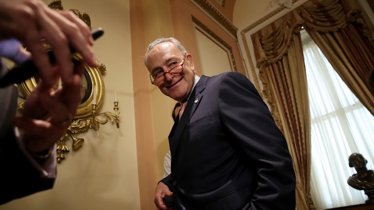 Chuck Schumer smiles as he leaves a press conference.