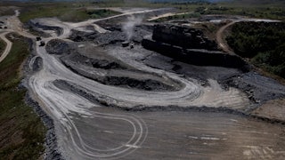 An aerial picture shows a grey expanse cut into the surrounding green landscape.