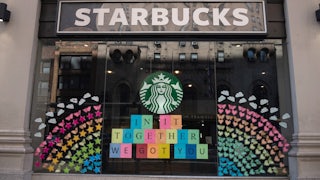 Starbucks storefront has a large rainbow made of hearts, stars, and butterflies, along with a sign that reads: "In it together / we got you"