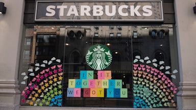 Starbucks storefront has a large rainbow made of hearts, stars, and butterflies, along with a sign that reads: "In it together / we got you"