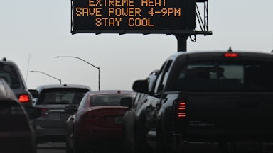 Cars sit in bumper-to-bumper traffic beneath a sign saying "Extreme Heat Save Power 4-9 PM Stay Cool."