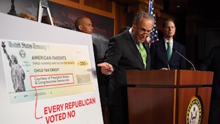 Senate Majority Leader Chuck Schumer points to a sign indicating that Republicans voted against the extension of the child tax credit.