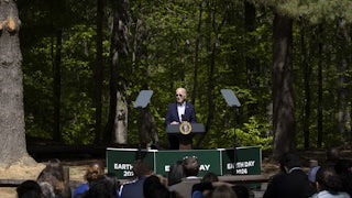 President Biden speaks at an "Earth Day 2024" podium in front of trees.