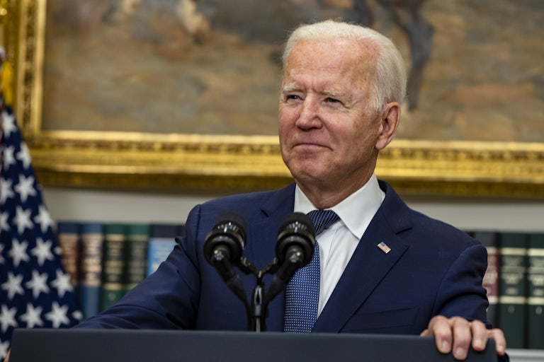 A close-up of Joe Biden, smiling behind a lectern.