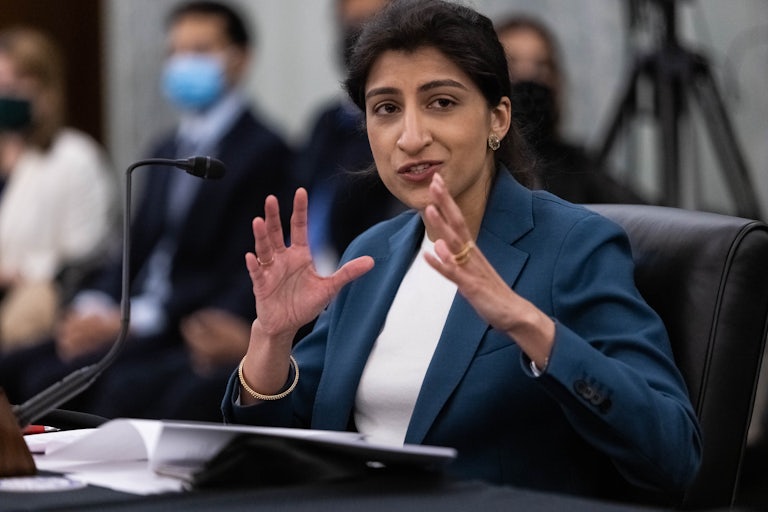 FTC Commissioner Lina M. Khan smiles and gestures with her hands while testifying during a Senate hearing 