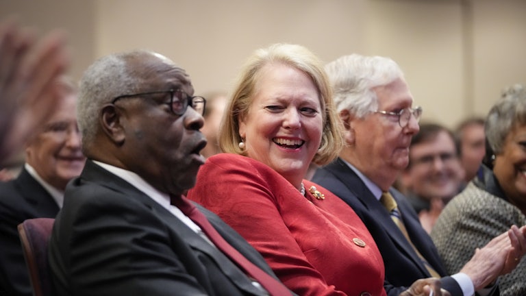 Conservative activist Virginia Thomas sits with her husband, Supreme Court Justice Clarence Thomas, while he waits to speak at the Heritage Foundation.