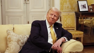 Donald Trump smiles while sitting on a couch