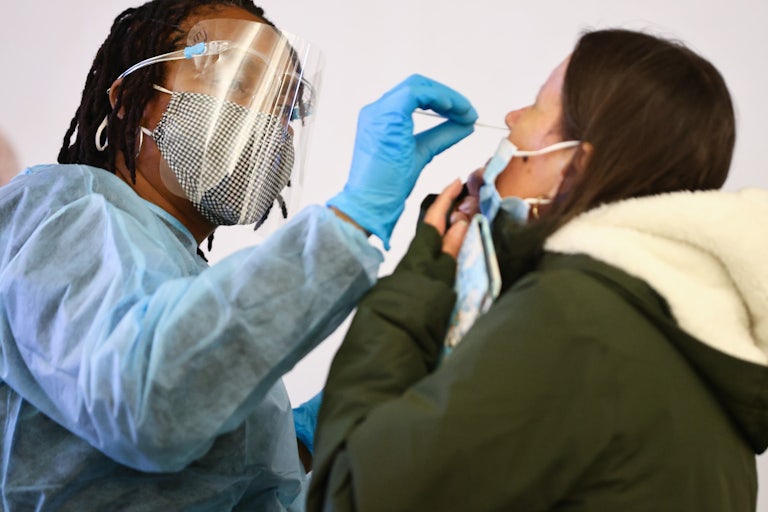 A health care worker swabs a person's nose.
