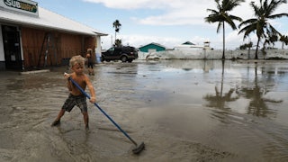 A child attempts to sweep away flood waters.