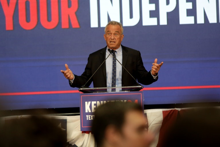 Robert F. Kennedy Jr. gestures as he speaks into microphones at a podium