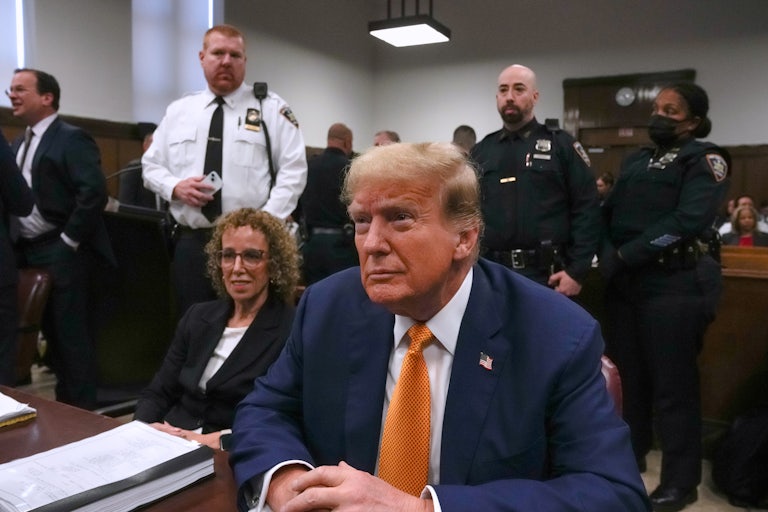 Donald Trump clasps his hands in court and smiles