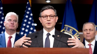 House Speaker Mike Johnson speaks at a podium while flanked by House Majority Whip Tom Emmer and House Majority Leader Steve Scalise