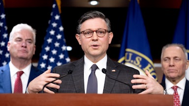 House Speaker Mike Johnson speaks at a podium while flanked by House Majority Whip Tom Emmer and House Majority Leader Steve Scalise