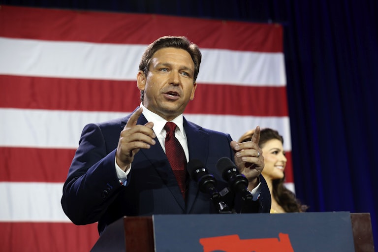 Ron DeSantis speaks at a podium and points with both index fingers