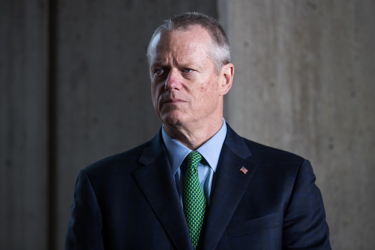 Massachusetts Governor Charlie Baker stands attentively at a press conference.
