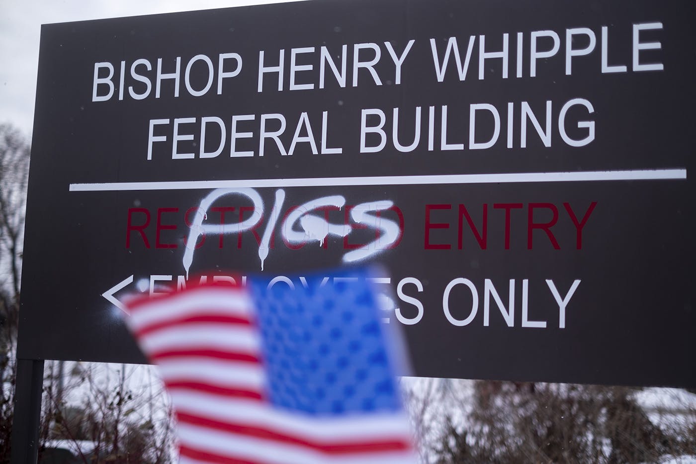 The entrance sign for the Bishop Henry Whipple Federal Building that has been changed with spray paint grafitti to read PIGS ENTRY ONLY