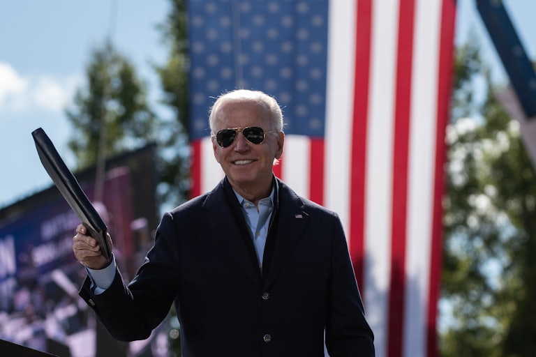 Democratic presidential nominee Joe Biden holds a binder in front of an American flag at a campaign event.