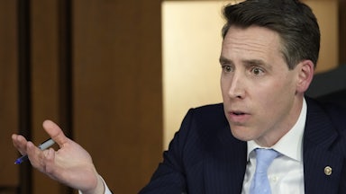 Josh Hawley looks exasperated and raises his hand in the air as if to question, "What?"