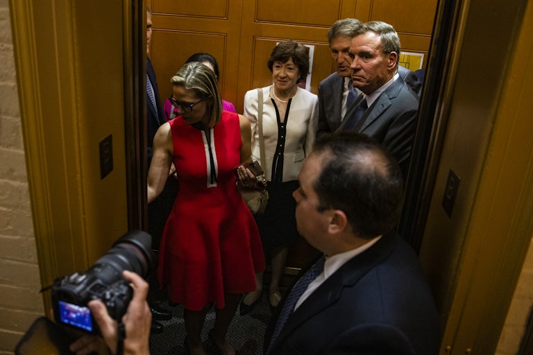 Senators Kyrsten Sinema, Susan Collins, Joe Manchin, and Mark Warner board an elevator in the Capitol building 