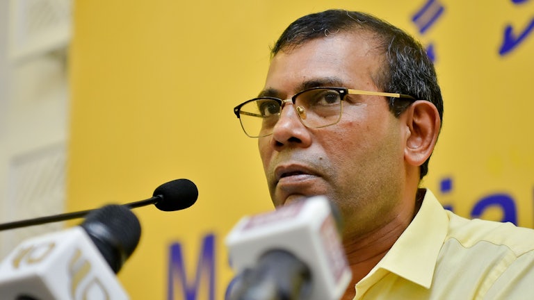 Mohamad Nasheed speaks in front of several microphones.