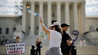 Demonstrators blow a shofar and hold a sign saying "abortion pills are murder."