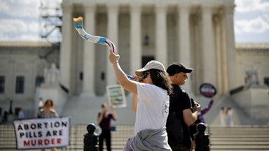 Demonstrators blow a shofar and hold a sign saying "abortion pills are murder."