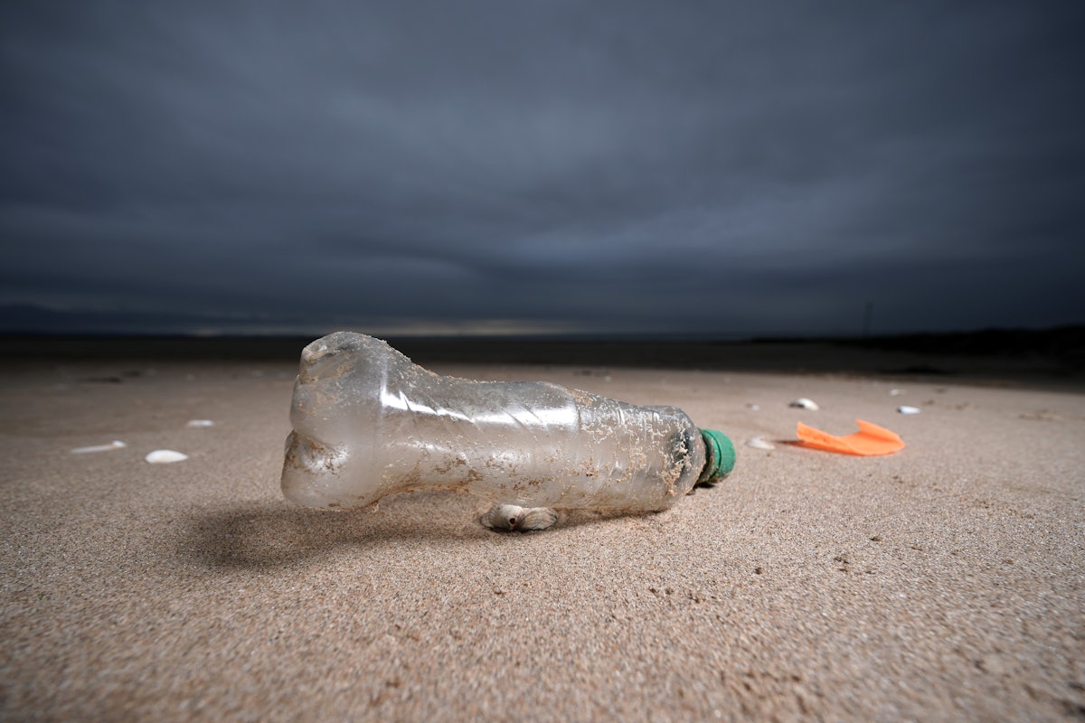 A plastic bottle lies on a beach.