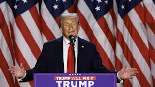 Donald Trump holds his arms out while speaking at a podium