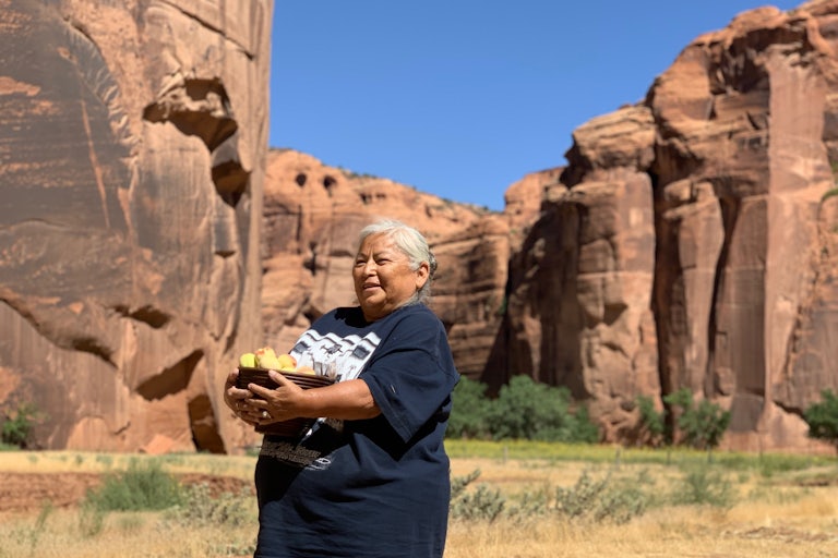 Sylvia Watchman holds a basket of peaches in Canyon de Chelly.