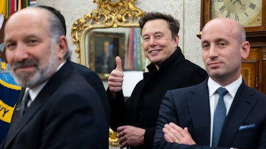 Elon Musk smiles and gives a thumbs-up sign, while standing between Howard Lutnick and Stephen Miller.