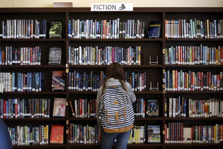 A child stands in front of a bookcase in the library
