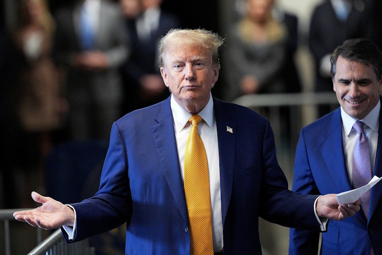 Trump holds his hands up in the air as if shrugging, while his attorney Todd Blanche laughs behind him