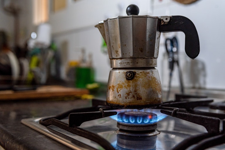 A coffee pot sits on a gas burner.