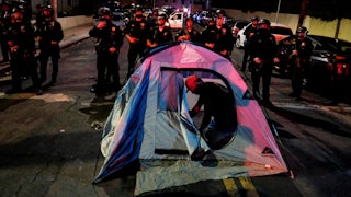 A man sets up a tent in front of police during a protest ahead of a planned and announced clean-up of a homeless encampment.