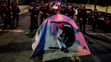 A man sets up a tent in front of police during a protest ahead of a planned and announced clean-up of a homeless encampment.