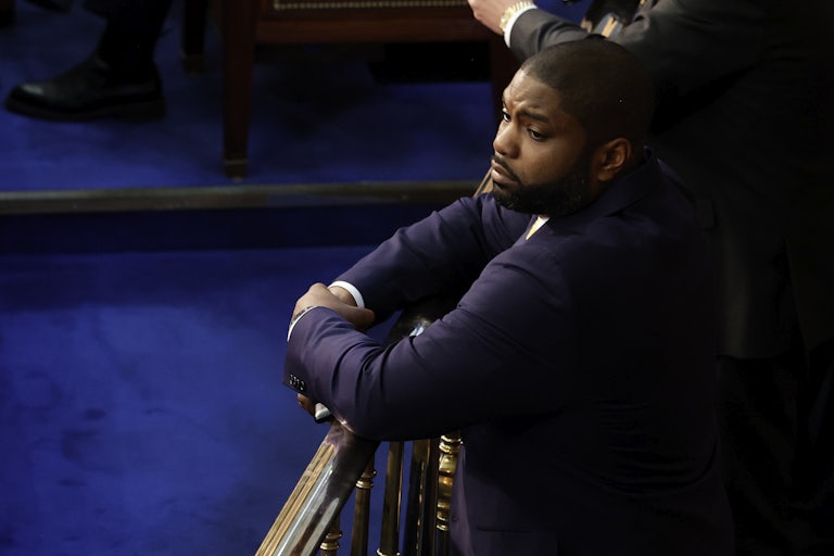 Representative Byron Donalds leans over a railing in the House chambers